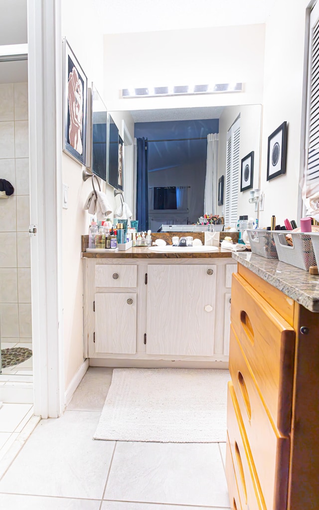 bathroom featuring vanity, tiled shower, and tile patterned flooring