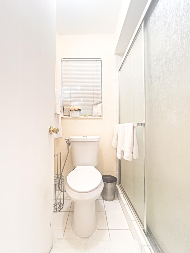 bathroom featuring a shower with door, toilet, and tile patterned floors