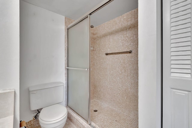 bathroom featuring toilet and a shower with door