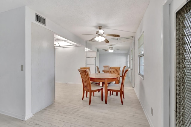 dining room featuring ceiling fan, light hardwood / wood-style floors, and a textured ceiling