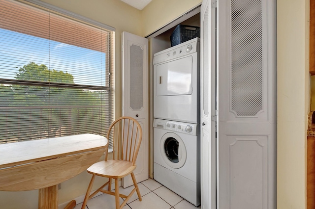 clothes washing area featuring light tile patterned floors and stacked washing maching and dryer