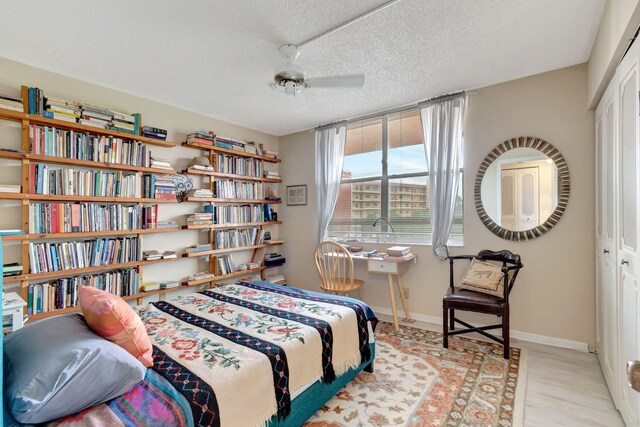 bedroom featuring ceiling fan, light hardwood / wood-style floors, a textured ceiling, and a closet