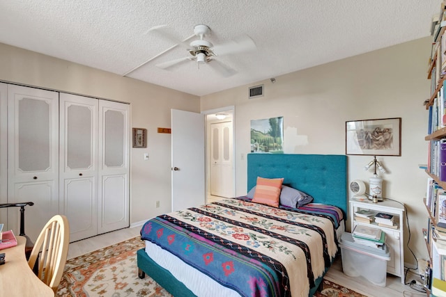 bedroom with a textured ceiling, a closet, light hardwood / wood-style floors, and ceiling fan