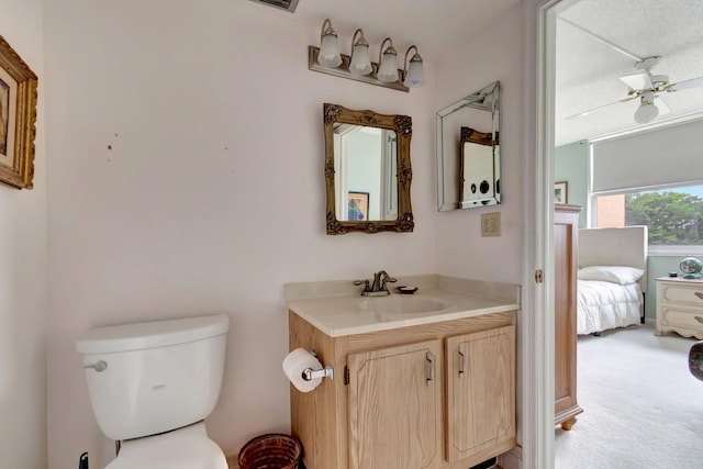 bathroom with ceiling fan, toilet, a textured ceiling, and vanity