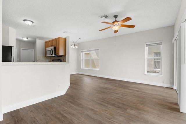 unfurnished living room with dark wood-type flooring, a textured ceiling, and ceiling fan with notable chandelier