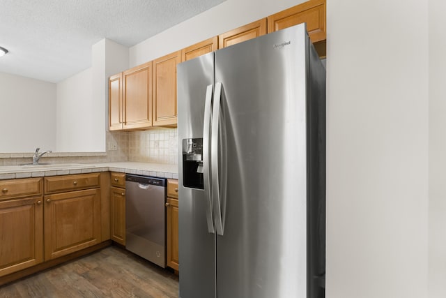 kitchen featuring decorative backsplash, appliances with stainless steel finishes, tile countertops, dark wood-type flooring, and sink