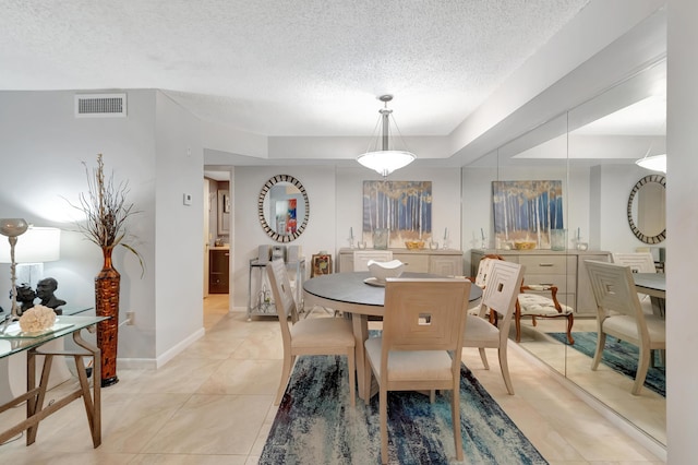 dining room with a textured ceiling, a raised ceiling, and light tile patterned flooring