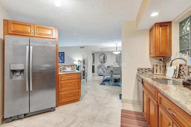 kitchen featuring backsplash, light stone counters, stainless steel appliances, sink, and light tile patterned flooring