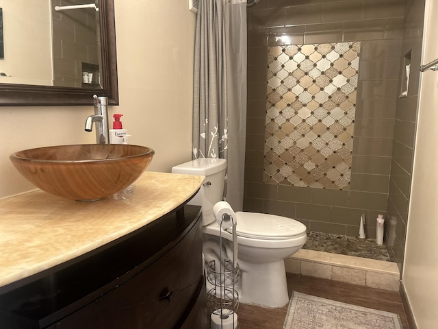 bathroom featuring walk in shower, vanity, wood-type flooring, and toilet