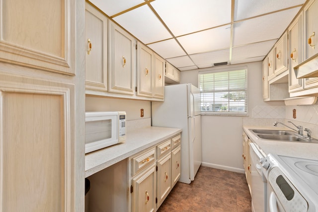 kitchen featuring sink, decorative backsplash, cream cabinetry, and white appliances