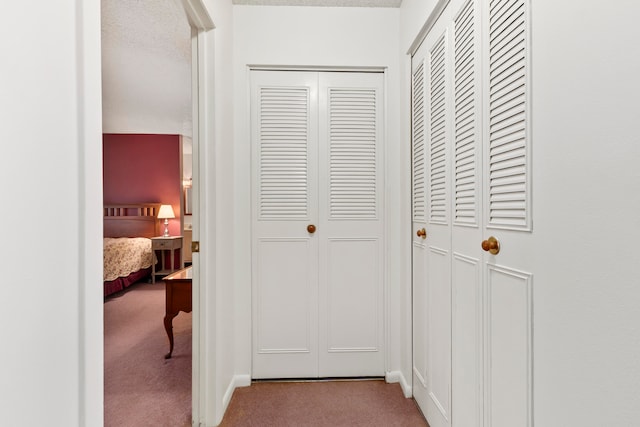 hallway with a textured ceiling and carpet floors