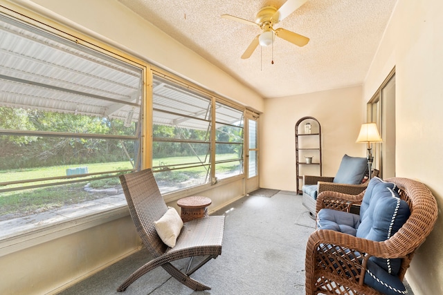 living area featuring ceiling fan, light carpet, and a textured ceiling