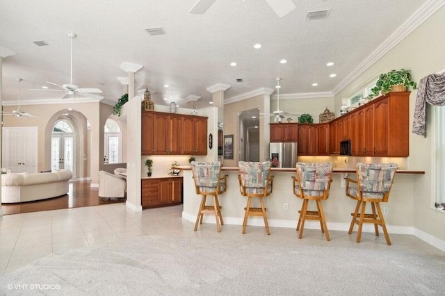 kitchen featuring a breakfast bar, crown molding, light tile patterned flooring, and stainless steel fridge with ice dispenser