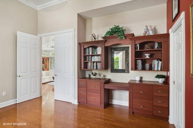 office area featuring built in desk, ornamental molding, and dark hardwood / wood-style floors