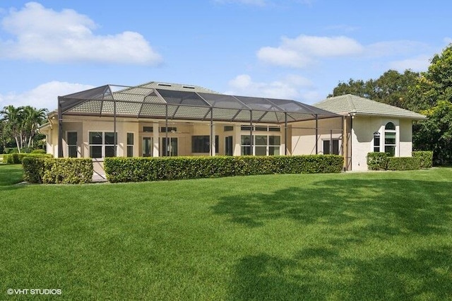 rear view of property featuring glass enclosure, ceiling fan, and a lawn