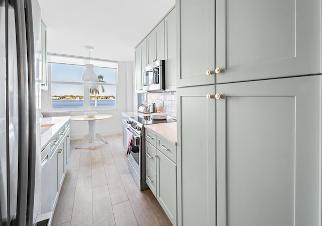 kitchen featuring breakfast area, stainless steel appliances, decorative light fixtures, decorative backsplash, and light hardwood / wood-style flooring