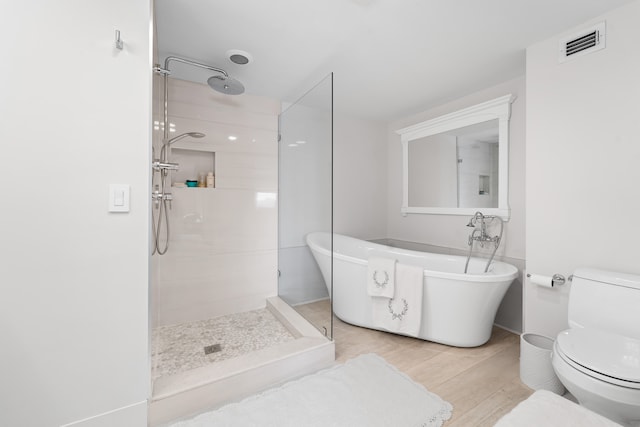 bathroom with shower with separate bathtub, hardwood / wood-style flooring, and toilet