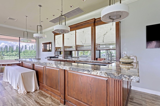 kitchen featuring crown molding, light stone countertops, and decorative light fixtures