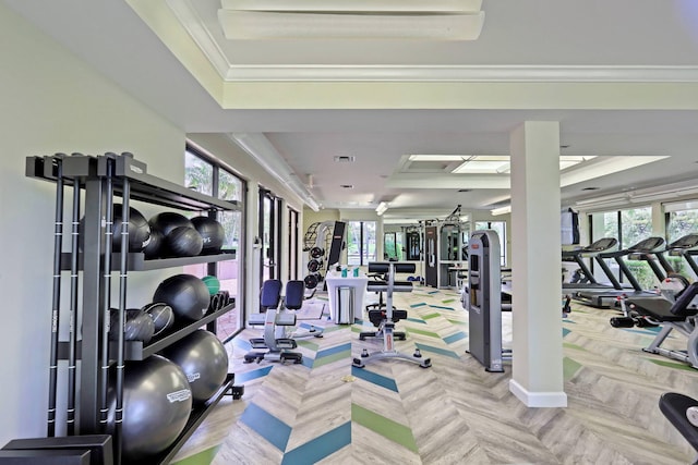 exercise room with a raised ceiling, plenty of natural light, and ornamental molding