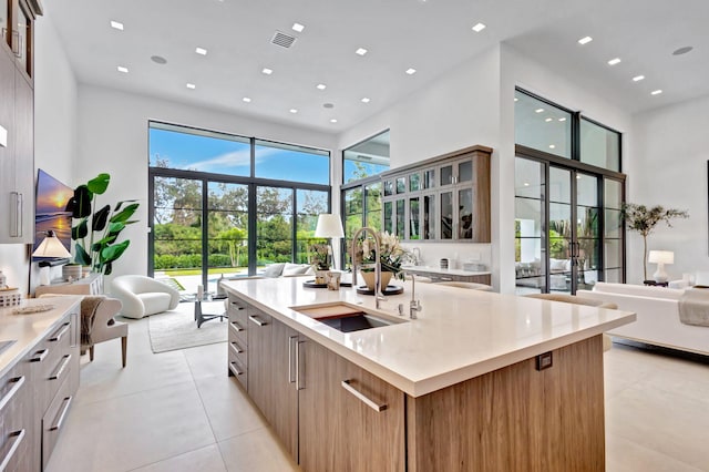 kitchen featuring a wealth of natural light, sink, a kitchen island with sink, and a high ceiling