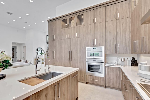 kitchen featuring ventilation hood, sink, light tile patterned floors, light stone counters, and stainless steel double oven