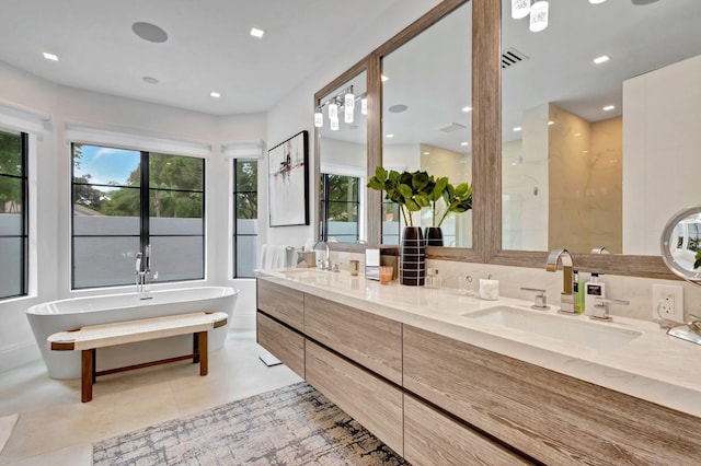 bathroom with tile patterned flooring, vanity, a tub to relax in, and tasteful backsplash