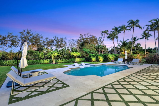 pool at dusk featuring a lawn and a patio area