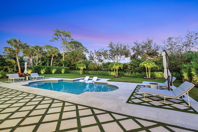 pool at dusk with a lawn and a patio area