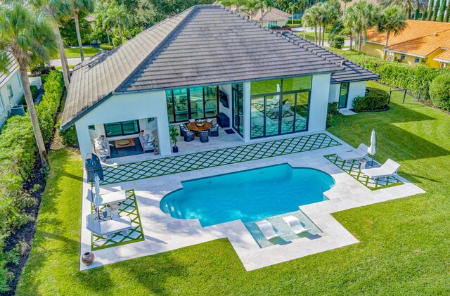 view of pool with outdoor lounge area, a patio, and a lawn