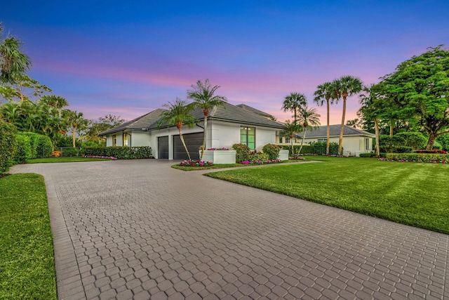 ranch-style house with a garage and a lawn