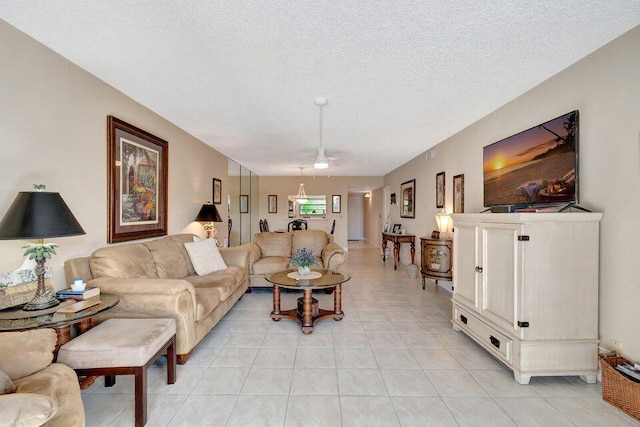 living room with ceiling fan, a textured ceiling, and light tile patterned floors