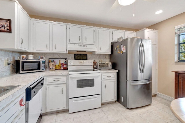 kitchen with stainless steel appliances, decorative backsplash, light tile patterned floors, and white cabinets