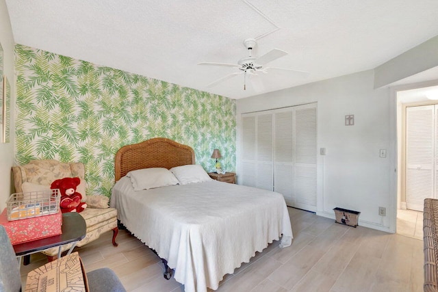 bedroom with light hardwood / wood-style flooring, a textured ceiling, a closet, and ceiling fan