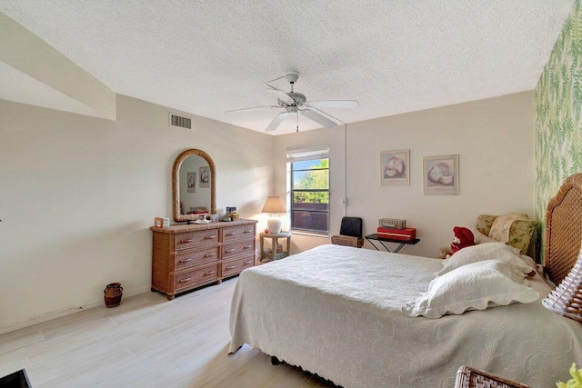 bedroom with light hardwood / wood-style floors, a textured ceiling, and ceiling fan