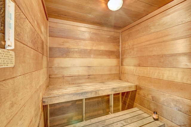 view of sauna featuring wood ceiling and wood walls