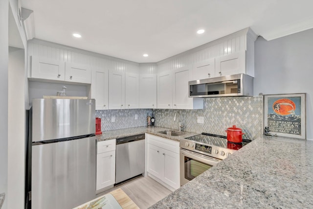 kitchen featuring sink, backsplash, stainless steel appliances, white cabinets, and light stone counters