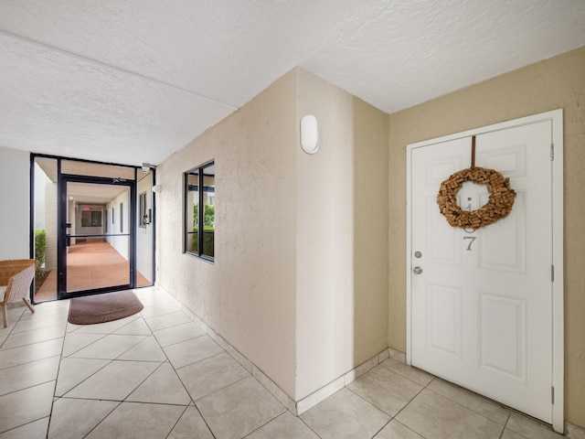 entryway with light tile patterned floors and a textured ceiling