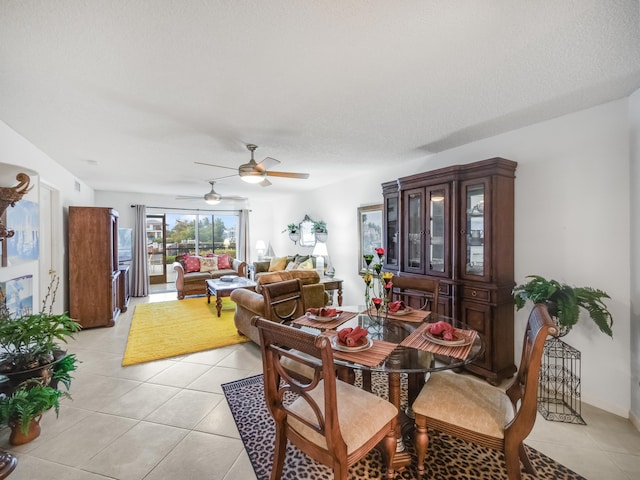 tiled dining area with ceiling fan and a textured ceiling