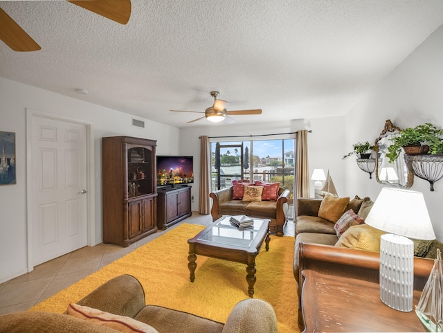 living room featuring a textured ceiling, ceiling fan, and light tile patterned flooring