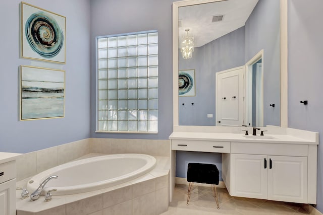 bathroom featuring tiled bath, tile patterned flooring, vanity, and an inviting chandelier