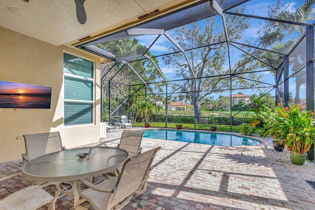 view of pool with glass enclosure, a patio, and ceiling fan