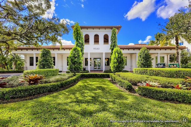 mediterranean / spanish-style house featuring a front lawn and french doors