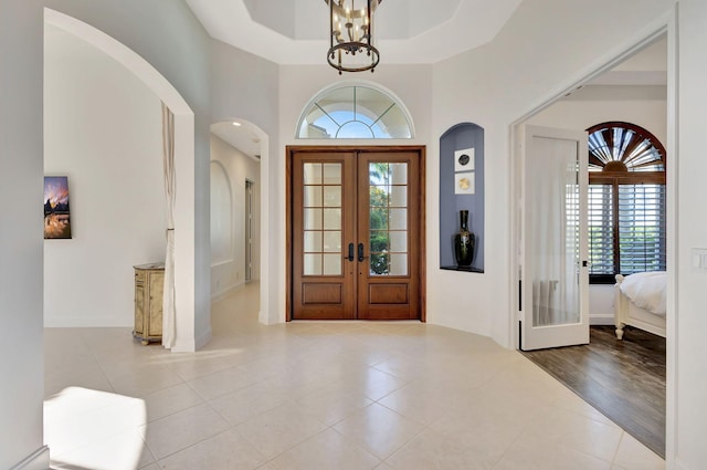 foyer with french doors, light hardwood / wood-style floors, and a raised ceiling