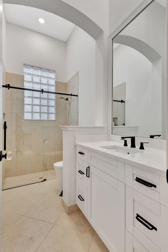 bathroom featuring a tile shower, vanity, tile patterned floors, and toilet