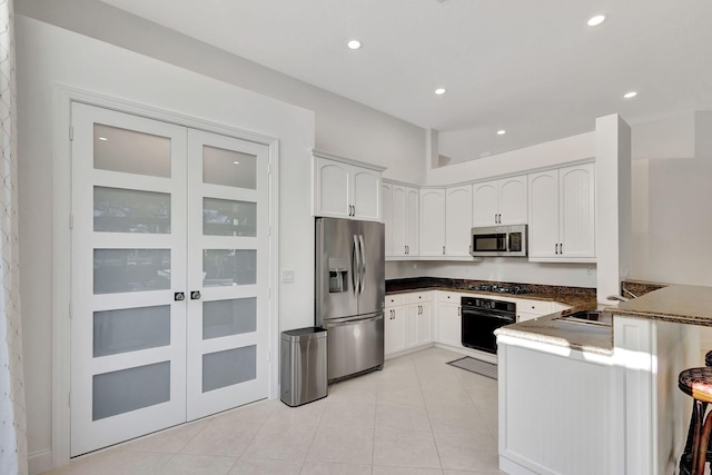 kitchen with sink, kitchen peninsula, appliances with stainless steel finishes, light tile patterned floors, and white cabinets