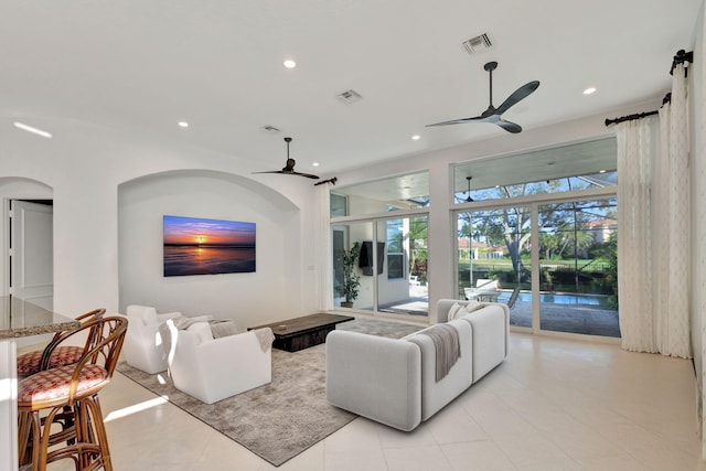 living room with a barn door, ceiling fan, and light tile patterned floors