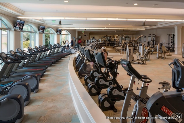 workout area with ornamental molding and light carpet