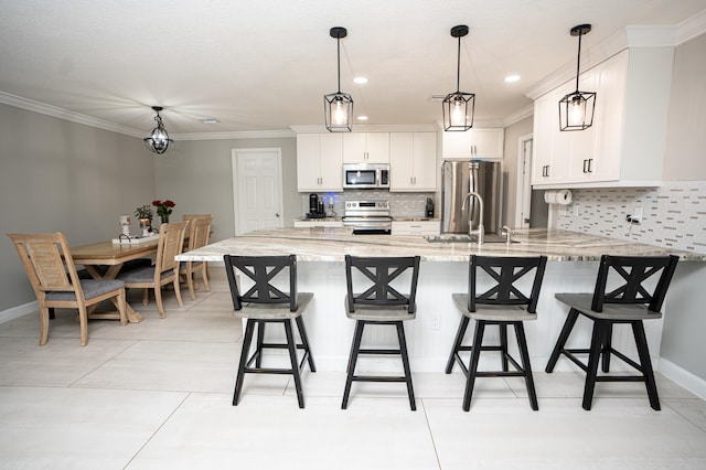 kitchen with stainless steel appliances, sink, decorative light fixtures, white cabinets, and light stone counters