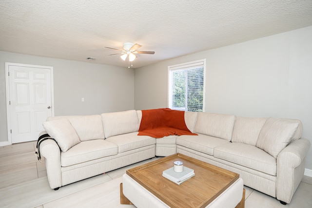 living room featuring ceiling fan, a textured ceiling, and light tile patterned floors