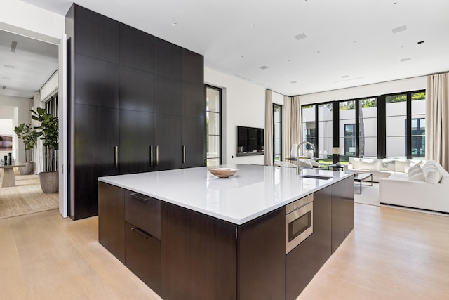 kitchen with a spacious island, light hardwood / wood-style flooring, stainless steel microwave, and sink